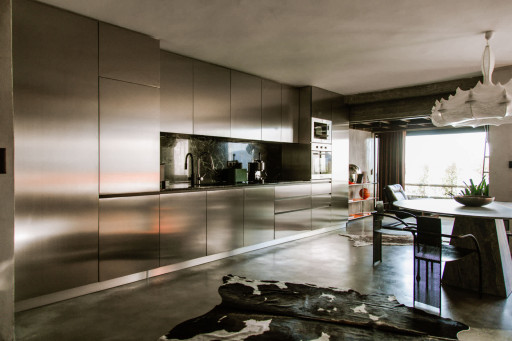Sleek stainless-steel kitchen wall with integrated appliances and minimalist architectural design.