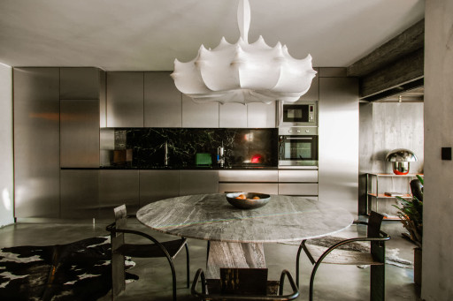Modern dining area set beside the designer kitchen with sculptural chandelier lighting.