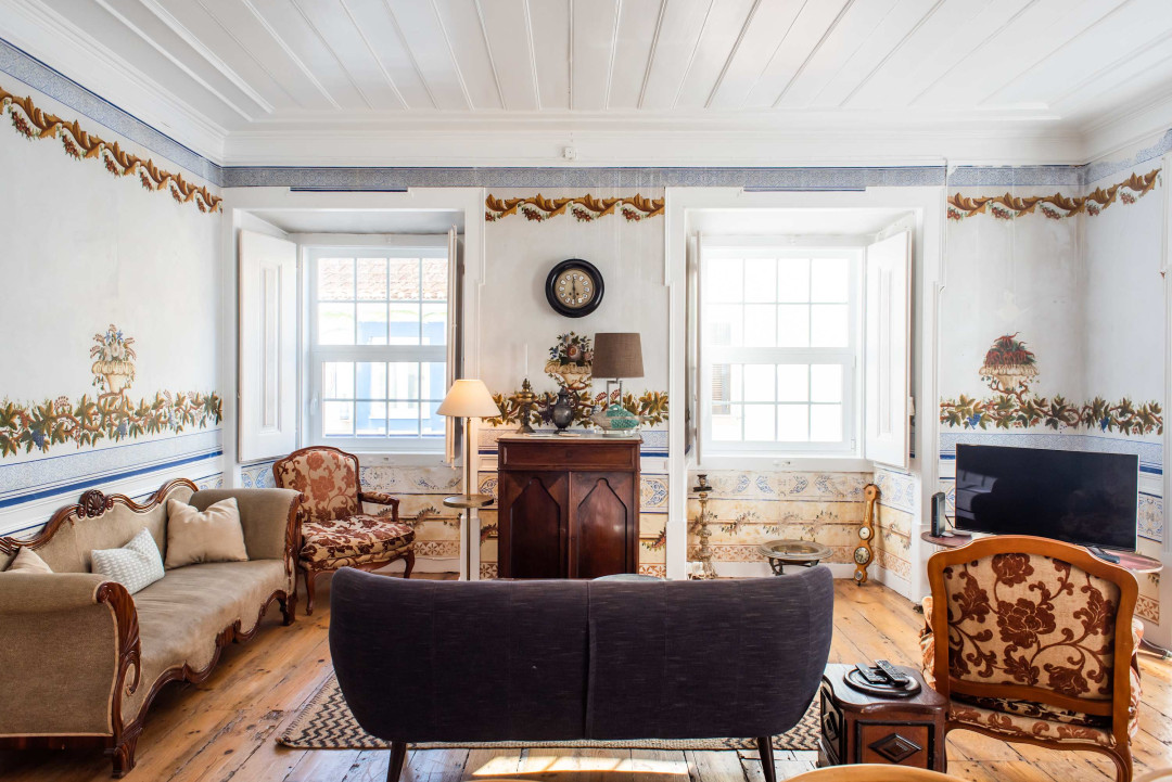 Santo Antonio 1 spacious living area with large windows, showcasing a blend of antique and modern furniture.