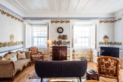 Santo Antonio 1 spacious living area with large windows, showcasing a blend of antique and modern furniture.
