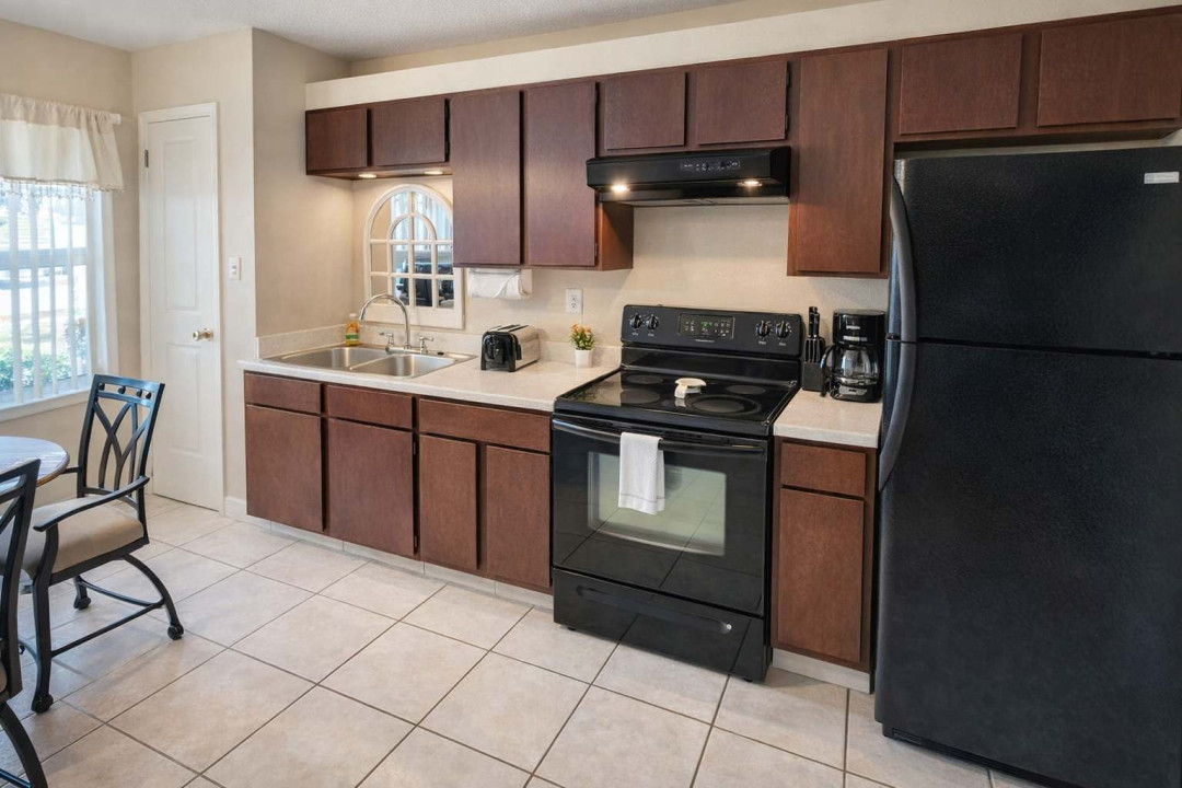 Modern kitchen with black appliances, double sink, and dining area—bright, clean, and fully equipped for your stay. Natural light, sleek finishes, and cozy charm make it perfect for short-term rental comfort.