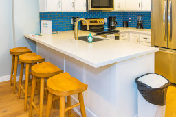 Cook and connect in this modern kitchen featuring sleek quartz countertops, stainless steel appliances and stylish blue tile backsplash. Perfect for casual breakfasts or entertaining guests, the nearby bar seating adds a warm, inviting touch.