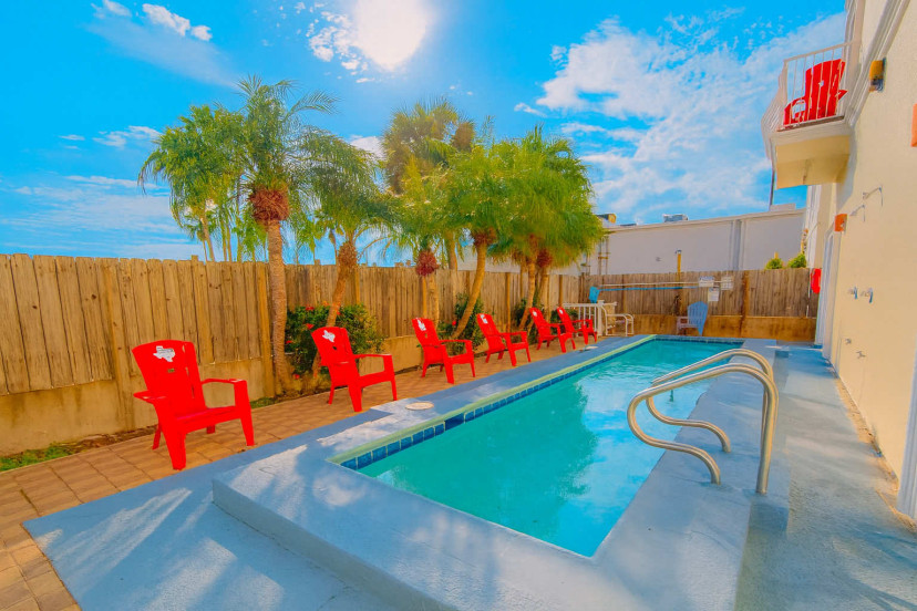Sunny Poolside Retreat with Red Chairs
Relax by this cozy, sparkling pool lined with bright red Adirondack chairs and tropical palm trees, perfect for sunbathing, morning swims, or evening cocktails in a quiet, fenced courtyard oasis.