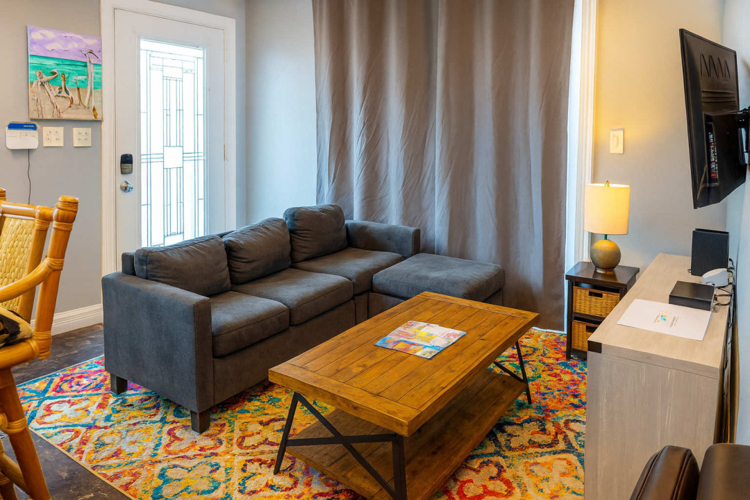 Cozy Living Room with Smart TV
Unwind in a comfy living area featuring a plush sectional sofa, rustic wood coffee table, colorful rug, and wall-mounted TV, perfect for movie nights, reading, or relaxing after a day at the beach.
