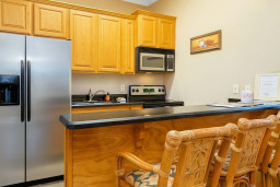 Cozy Full Kitchen with Bar Seating
Enjoy a fully equipped kitchen with stainless steel fridge, stove, microwave, double sink, and granite bar counter with comfortable stools, ideal for cooking meals, quick breakfasts, or relaxing with drinks.