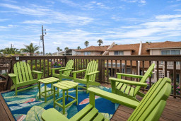 Tropical deck retreat with 6 vibrant Adirondack chairs, lush palm views, and colorful rug—perfect for morning coffee or sunset chats in a coastal neighborhood. Relax, unwind, and soak in the beachside vibes.