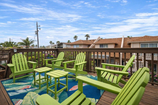 Tropical deck retreat with 6 vibrant Adirondack chairs, lush palm views, and colorful rug—perfect for morning coffee or sunset chats in a coastal neighborhood. Relax, unwind, and soak in the beachside vibes.