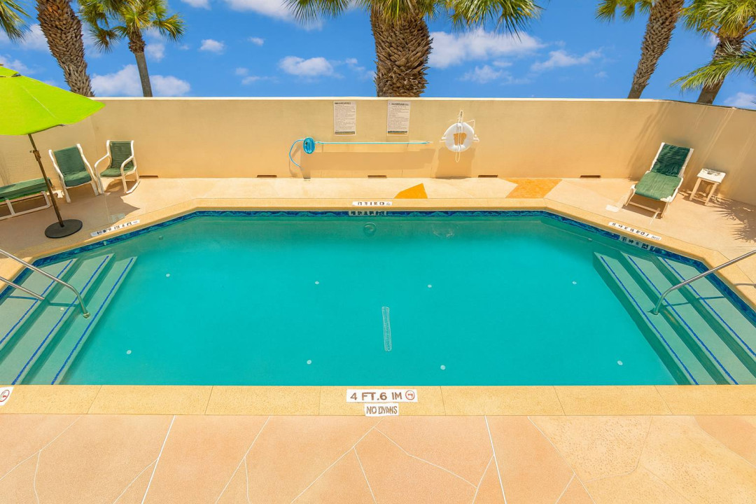 Unwind and soak up the sun at the sparkling swimming pool, complete with lounge chairs, umbrellas, and plenty of relaxing space for your vacation enjoyment. The perfect spot to cool off after a day at the beach!