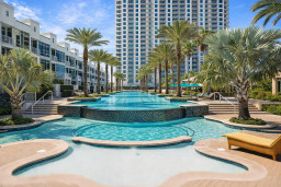 Luxurious resort-style pool with cascading tiers, palm-lined deck, and modern high-rise views—perfect for relaxing under the sun or enjoying a tropical escape in a vibrant, upscale community.