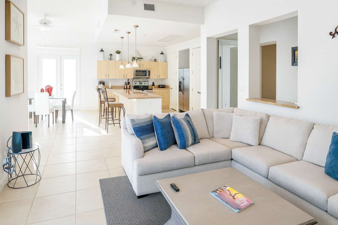 Open-Plan Living & Dining Area
Spacious living room flows seamlessly to dining and kitchen with plush sectional sofa, ceiling fans, and abundant natural light. Gather for games or meals near balcony doors—cozy coastal vibes for unforgettable stays!