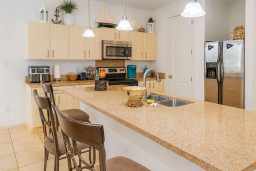 Coastal Kitchen with Bar Seating
Bright, fully equipped kitchen boasts granite counters, stainless appliances, and nautical decor. Perch on bar stools for casual meals amid wood cabinets and pendant lights—cook up beach day feasts effortlessly!