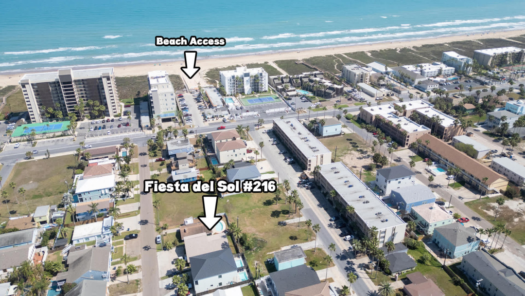 Aerial view of a vibrant coastal community with sandy shoreline, nearby amenities, and easy beach access. A prime location that offers guests convenience, walkability, and a relaxed seaside atmosphere perfect for effortless vacation living.