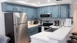 Modern kitchen with blue‑gray cabinetry, stainless appliances, and a bright island workspace. Patterned tile backsplash and thoughtful essentials create a clean, functional space perfect for cooking, gathering, and effortless vacation living.