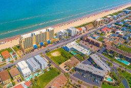 Vibrant Beachfront Resort Aerial Vista
Soar above this lively Gulf Coast paradise: pristine sands meet turquoise waves, dotted with umbrellas and beachgoers. Multi-story condos and hotels line the shore amid colorful homes and pools.