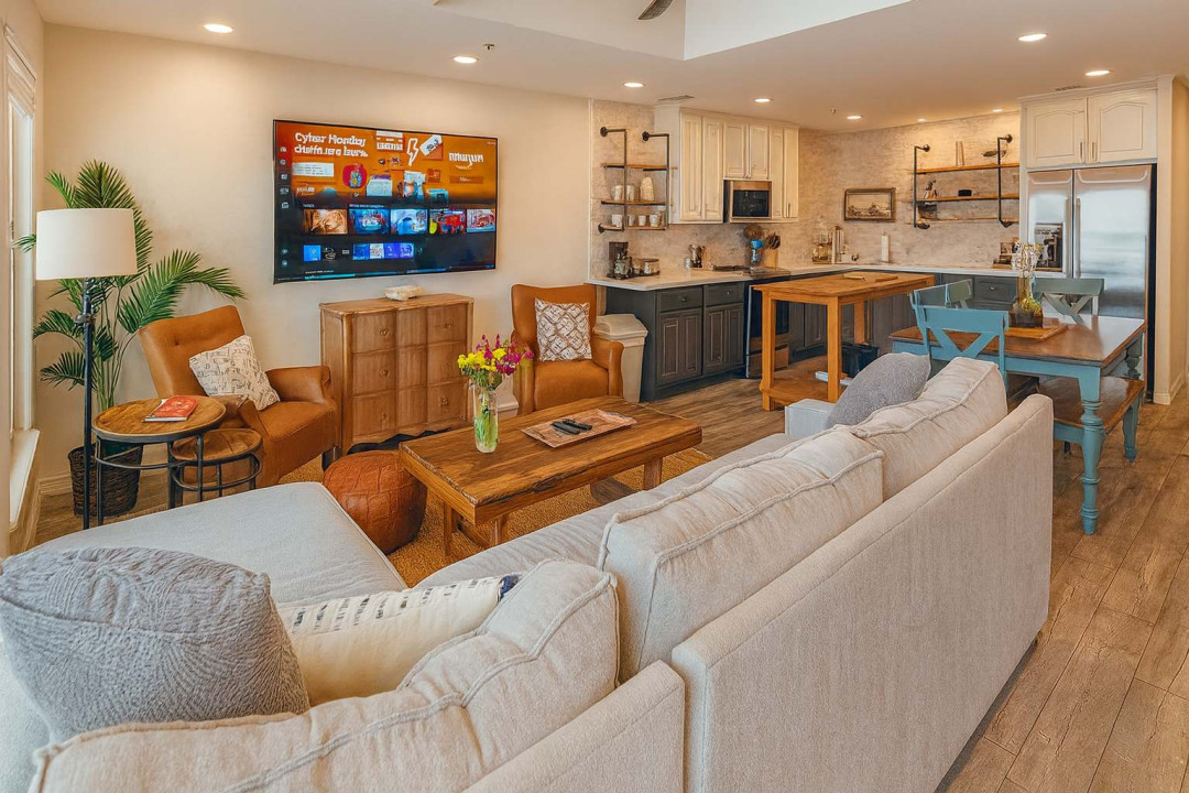 Cozy Open-Plan Living & Dining Area
Relax in this bright, beachy living space featuring plush sectional sofa, large wall-mounted TV streaming favorites, and tropical plants. Wood-accented dining table seats comfortably near the sleek kitchen.