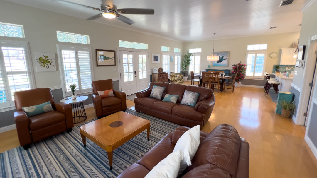 Bright, open living with coastal charm—this spacious great room features comfy leather seating, abundant natural light, a large dining area & a modern kitchen. Ideal for gathering, relaxing or entertaining in a refreshing, beach-inspired atmosphere.