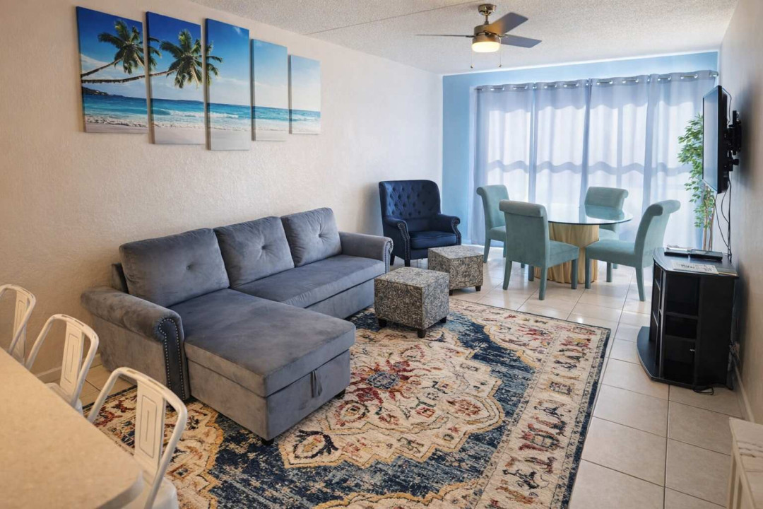 Bright coastal retreat with stylish living & dining, tropical wall art, natural light, and comfy seating. Steps from the beach, perfect for families or couples. Fast Wi-Fi, smart TV, and full kitchen with bar seating.