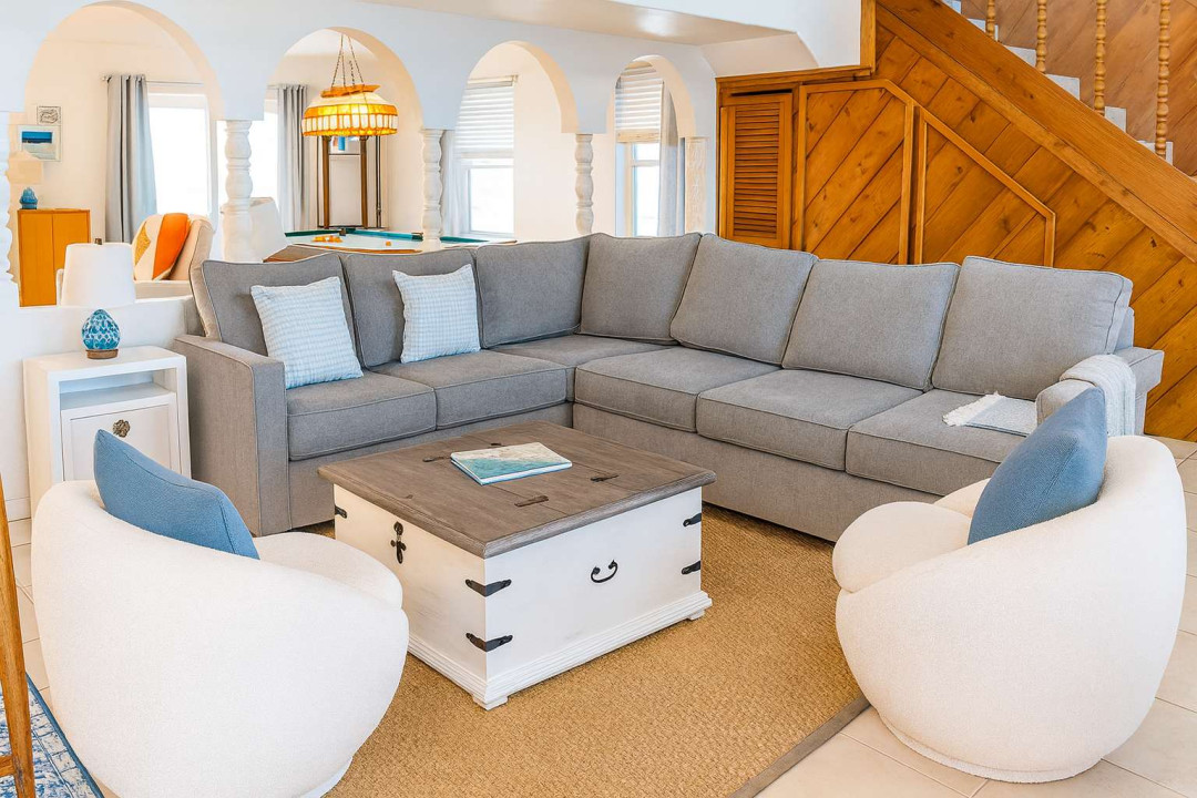 Relax in the inviting living room with a plush sectional, chic swivel chairs and stylish accents. Spacious, light-filled layout is perfect for game nights or unwinding. Enjoy comfort and coastal charm just steps from entertainment & gathering spaces.