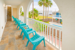 Enjoy morning coffee or sunset views from the spacious balcony, featuring comfortable turquoise chairs and serene tropical scenery. This perfect outdoor spot invites relaxation, gatherings, and unwinding in the fresh coastal air above the palm trees.