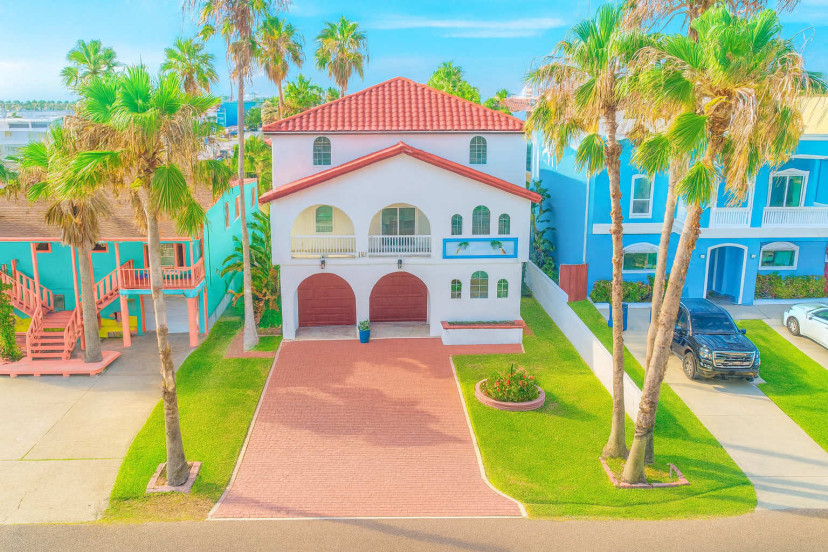 Bright, spacious beach home with tropical flair, featuring arched windows, private balconies, and lush palm trees. Steps from the ocean, this two-story retreat offers plenty of natural light, parking, and stunning curb appeal—perfect for relaxation.