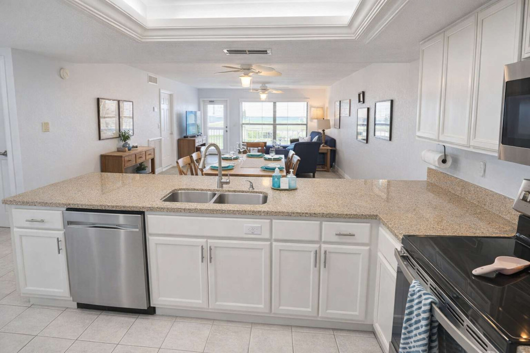 Modern open-concept kitchen & living area with granite counters, stainless steel appliances, natural light, and cozy seating—perfect for relaxing or entertaining in style.