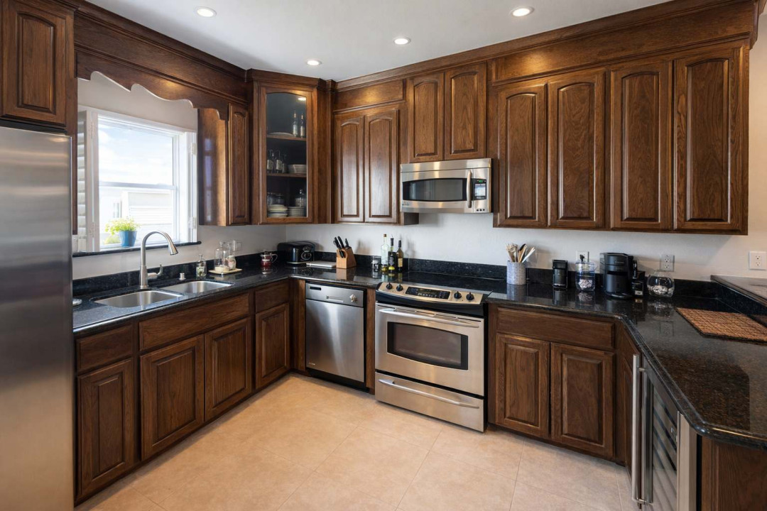 Modern kitchen with sleek stainless steel appliances, rich wood cabinetry, granite countertops, wine cooler, and coffee station—perfect for cooking, entertaining, and relaxing in style.