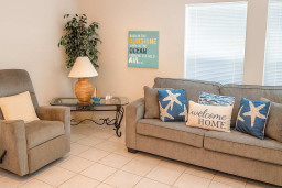 Relax in a welcoming living space with plush seating, cozy throw pillows, and cheerful coastal decor. The inviting lounge is perfect for kicking back after a day at the beach or enjoying family time in comfort and style.