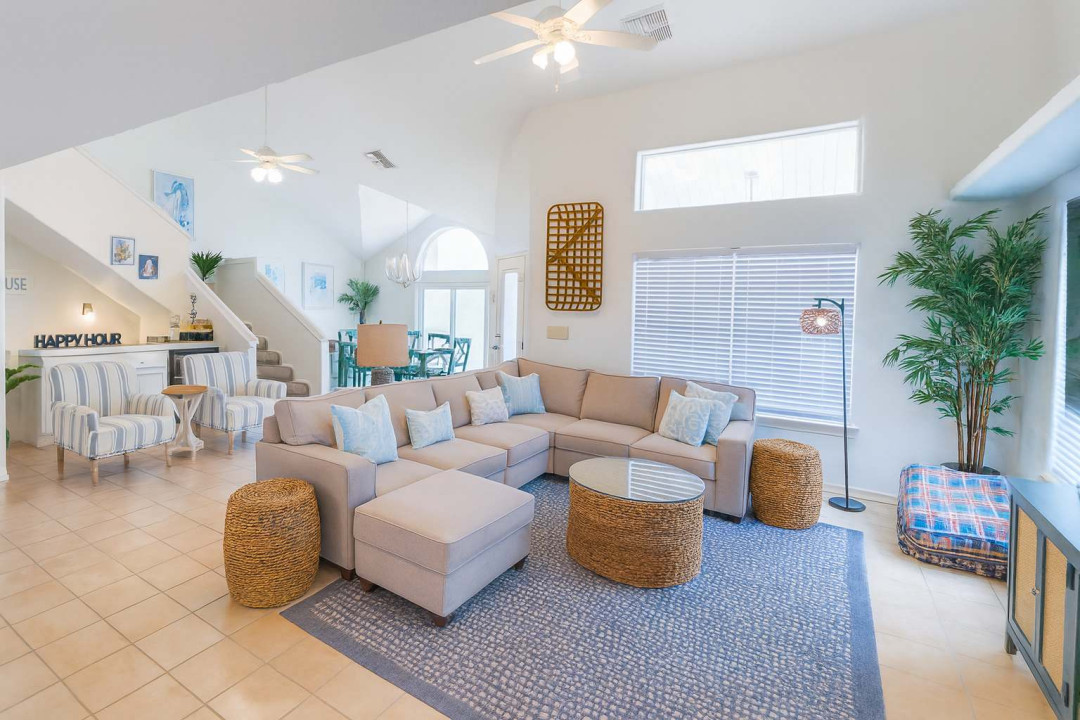 Spacious open-concept living area featuring a cozy sectional sofa, accent chairs, and a stylish wet bar. Natural light pours in from stunning arched windows, creating an inviting space perfect for socializing and family gatherings.