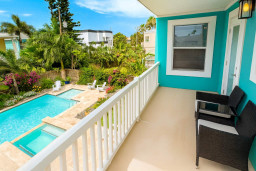 Relax on the private balcony overlooking lush gardens and a sparkling pool. Enjoy turquoise coastal vibes, comfy seating, and plenty of sunshine—the perfect spot for morning coffee or unwinding after a day at the beach.