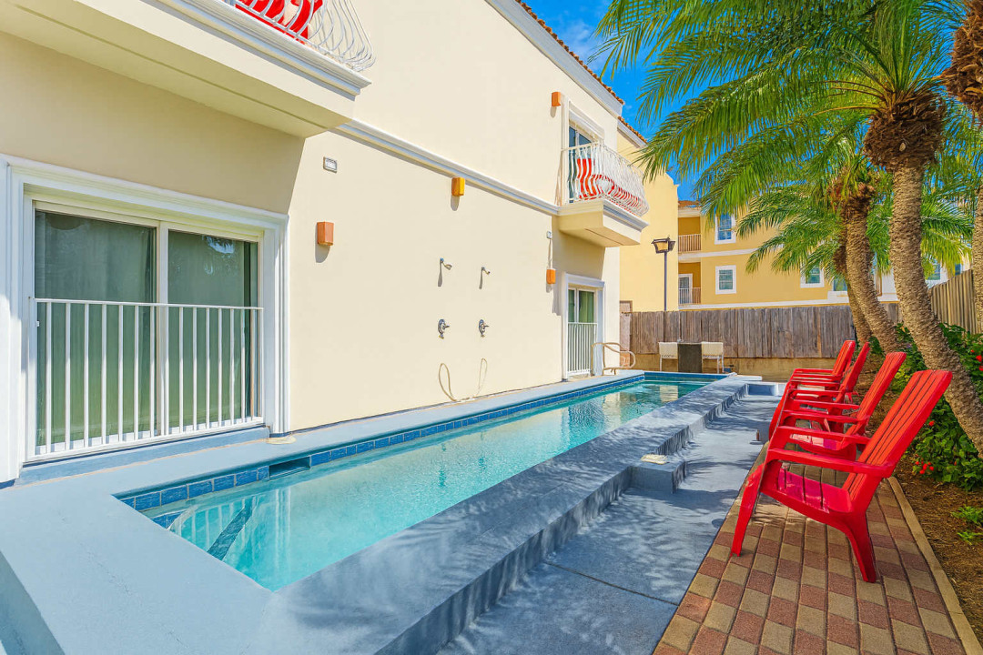 Sunlit Poolside Balcony Retreat
Enjoy the sleek lap pool framed by red loungers and swaying palms, just outside your stucco balcony with bistro chairs. Rinse off at outdoor showers and soak up coastal sunshine in privacy.