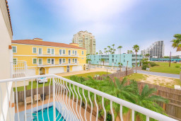 Balcony View of Coastal Condos
Sip morning coffee on your private balcony overlooking palm trees, the pool below, colorful yellow and teal condos, and distant high-rises. Peaceful neighborhood backdrop with plenty of coastal charm.