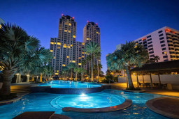 Luxurious Poolside Retreat with Skyline Views – Tropical Ambiance, Illuminated Nighttime Setting, Palm-Lined Oasis, Steps from Beach & Dining