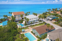 A bright coastal setting with homes tucked among palms and turquoise water nearby, offering an easygoing place to settle in, enjoy the relaxed neighborhood energy, and take in the simple charm of a breezy seaside community.