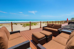 Oceanfront deck with plush seating, panoramic beach views, and resort-style relaxation under sunny skies.