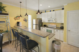 Cheerful Coastal Kitchen with Granite Breakfast Bar, Stainless Appliances & Bright Yellow Walls – Perfect for Relaxed Island Living