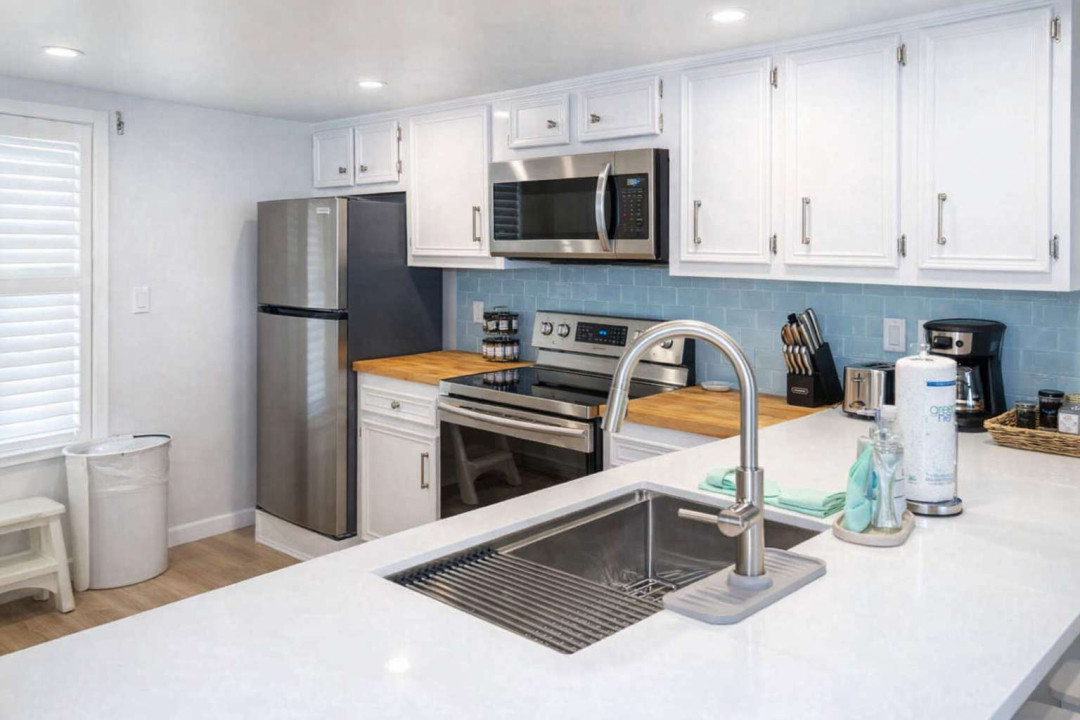 Bright, modern kitchen with stainless steel appliances, butcher block counters, subway tile backsplash, and natural light—perfect for cooking and entertaining in a clean, stylish space.