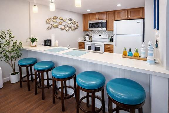 Bright, welcoming kitchen with warm wood tones and coastal pops of turquoise. A clean, airy space that feels instantly relaxing — perfect for slow mornings, shared meals, and effortless vacation living.