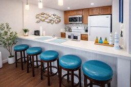 Bright, welcoming kitchen with warm wood tones and coastal pops of turquoise. A clean, airy space that feels instantly relaxing — perfect for slow mornings, shared meals, and effortless vacation living.