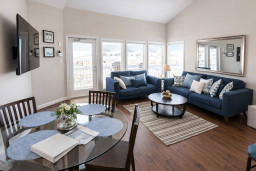 Sun‑filled living and dining space with coastal charm — soft blues, warm wood, and natural light create a relaxed, welcoming vibe perfect for unwinding after beach days or sharing easy meals with family and friends.
