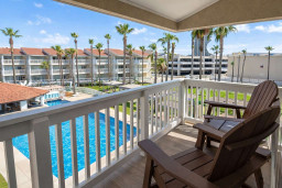 Serene balcony retreat overlooking a sparkling pool and palm-lined resort grounds — perfect for slow mornings or sunset unwinds. A calm, coastal vibe invites guests to relax and soak in the view, capturing effortless vacation ease.