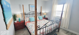Bright and inviting primary bedroom featuring a wrought‑iron canopy bed, floral linens, turquoise accents, and abundant natural light — a relaxing retreat designed for comfort and style.