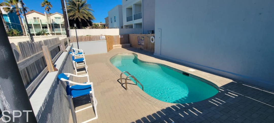 Inviting courtyard pool with turquoise water, sun loungers, and a private, palm‑lined setting — a relaxing outdoor escape perfect for cooling off after a day at the beach.