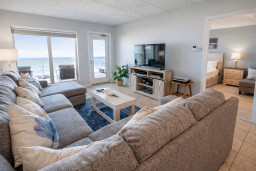 Sunlit coastal retreat blending comfort and calm — a spacious living area flows into a serene bedroom, inviting guests to unwind amid soft tones, natural light, and effortless connection to the outdoors.