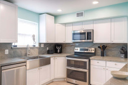 Modern Kitchen with Stainless Steel Appliances, Marble Counters, Farmhouse Sink & Natural Light—Perfect for Cooking & Entertaining