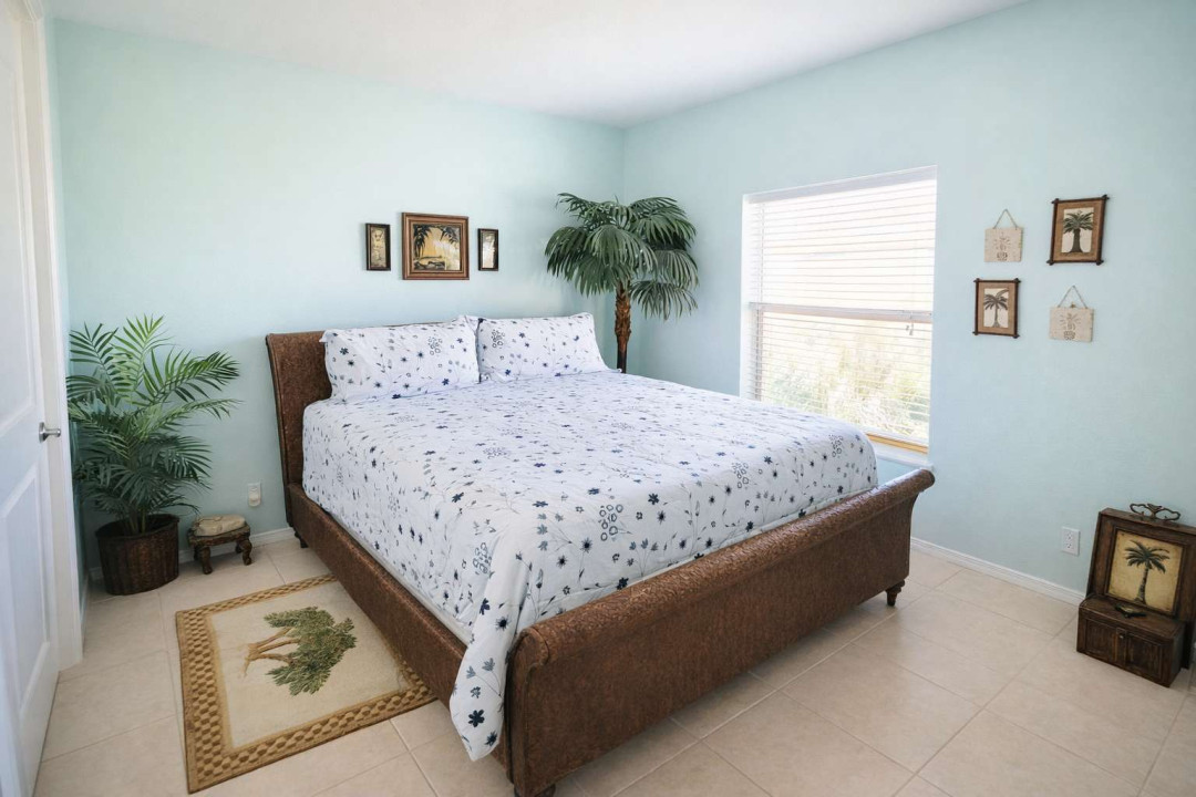 Tropical retreat with serene bed, lush palms, serene pastel walls, natural light, and coastal charm—perfect for a relaxing island escape near the beach. Clean, bright, and thoughtfully styled for your ideal getaway.