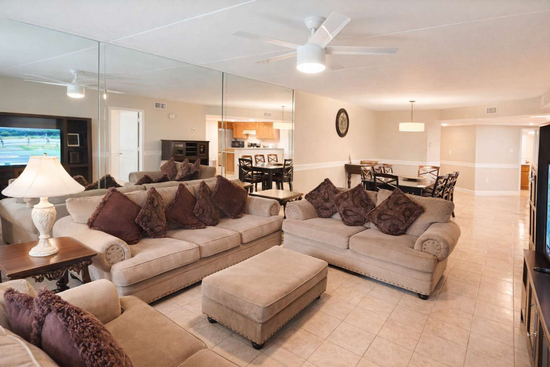 Spacious coastal retreat with open-concept living, plush seating, mirrored wall, and full kitchen—perfect for relaxing or entertaining near the beach.