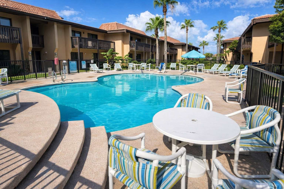 Relax in this tropical poolside retreat featuring a freeform swimming pool, striped lounge chairs, shaded tables, and palm-lined views—perfect for sun-soaked getaways and laid-back outdoor living.