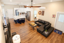 Open Kitchen-Living Retreat
Sleek white kitchen island flows to plush black leather sectional & TV! Modern lighting, wood floors at 114 Pike St Unit A, SPI. Direct beach access—ideal for family feasts & chill vibes.