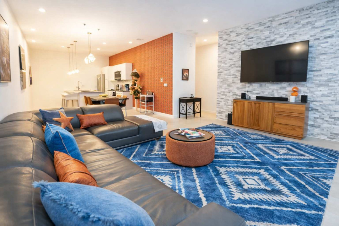 Sunlit open‑concept retreat blending cozy textures and modern design. Relax on the plush sectional, enjoy warm tones and stylish accents that create a welcoming, effortless flow between living and kitchen spaces.