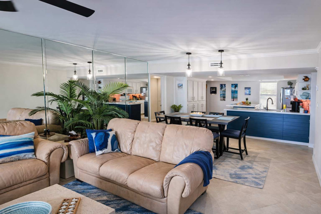 Stylish open-concept retreat with plush seating, mirrored wall, blue kitchen island, and dining for 8—perfect for group getaways near the coast.